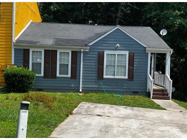 Charming blue home with a well-maintained lawn and a paved driveway at 6470 Bedford Ln, Lithonia, GA 30058