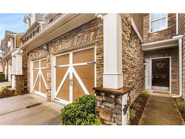 Stunning townhome exterior featuring stone facade, two-car garage and inviting entrance with beautiful landscaping at 6038 Mayfield Se Way, Mableton, GA 30126