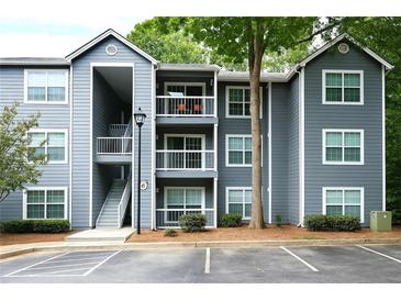 Three-story condo building featuring light gray siding, white trim, balconies, and staircase entryway at 5207 Santa Fe Pkwy, Sandy Springs, GA 30350