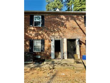 Brick townhouse exterior featuring black shutters, open front door, and patio area at 106 Plantation Dr, Clarkston, GA 30021