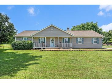 Charming single-story home featuring a well-manicured lawn and inviting front porch with rocking chairs at 487 Laney Rd, Locust Grove, GA 30248