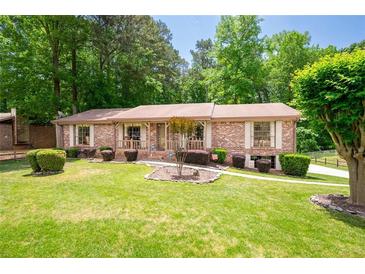 Charming brick home featuring a well-manicured front yard with mature trees and established landscaping at 655 Stone Harbor Sw Pkwy, Marietta, GA 30060