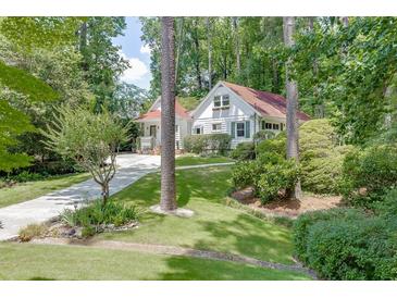 Charming cottage-style home with beautiful landscaping, a stone walkway and driveway through lush greenery at 3219 Parkridge Crescent, Chamblee, GA 30341