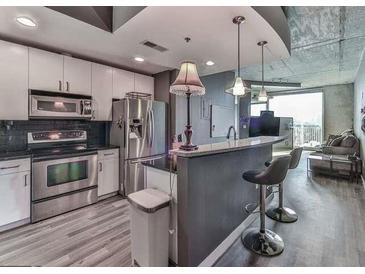 Modern kitchen with stainless steel appliances, light cabinets, bar seating, and industrial style lighting at 361 17Th St # 1121, Atlanta, GA 30363