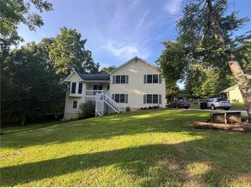 Charming two-story home with a white stairway, blue shutters and a lush green lawn at 1365 Rockmart Rd, Villa Rica, GA 30180