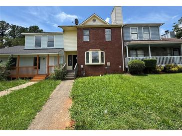 Charming two-story townhome with brick facade and inviting front entrance, surrounded by lush landscaping at 8170 Canyon Forge Dr, Riverdale, GA 30274