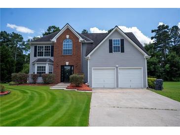 Charming two-story home featuring a manicured lawn, two-car garage, and classic architectural details at 2504 Hannah Haven Dr, Conyers, GA 30012