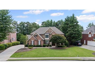 Beautiful brick home features a manicured lawn and mature trees, enhancing its curb appeal at 3560 Greenside Ct, Dacula, GA 30019