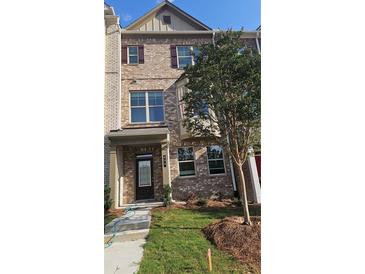 Charming brick townhome featuring a covered entry, multiple windows, and landscaped front yard at 539 Fundao Ln # 28, Lawrenceville, GA 30046