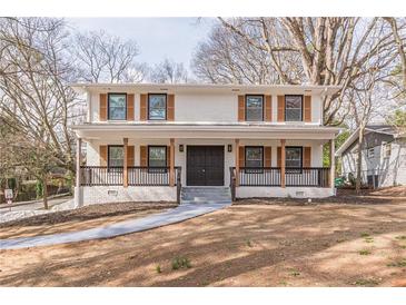 Inviting two-story home featuring a brick facade, a cozy front porch, and a well-manicured front yard at 1885 N Druid Hills Ne Rd, Atlanta, GA 30319
