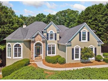 Charming home featuring manicured landscaping, stone accents, arched windows, and black shutters at 3845 Overlake Dr, Cumming, GA 30041