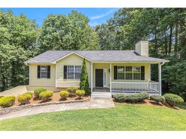 Charming yellow home with well-manicured lawn, front porch, and mature trees at 7420 Bristol Cir, Douglasville, GA 30134