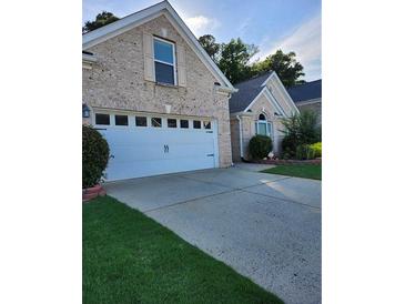 Charming brick home featuring a two-car garage, a well-maintained lawn, and an inviting driveway at 979 Simonton Glen Dr, Lawrenceville, GA 30045