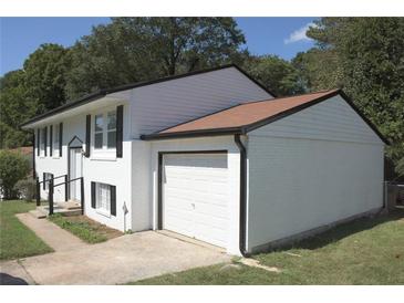 Charming two-story home featuring white painted brick, siding, a two-car garage, and a well-manicured lawn at 1417 Pineglen Dr, Riverdale, GA 30296