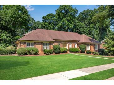 Charming brick home featuring lush green lawn, mature landscaping, and inviting curb appeal at 4063 Penhurst Dr, Marietta, GA 30062