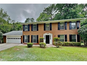 Charming two-story brick home featuring a well-manicured lawn and a two-car garage, complete with traditional black shutters at 650 Lake Forest Ct, Roswell, GA 30076