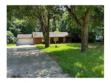 View of the home's exterior with an attached garage and mature trees on a grassy lot at 2842 Jordan Forest Trail Northwest, Lawrenceville, GA 30044