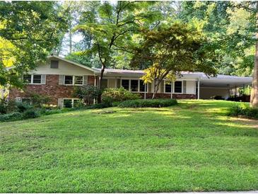 Charming single Gathering home with brick accents, a well-manicured lawn, and a covered carport at 1646 Rainier Falls Ne Dr, Atlanta, GA 30329