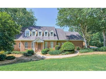 Charming brick home featuring dormer windows, mature trees and a well-manicured lawn at 4070 Runnnymede, Lilburn, GA 30047