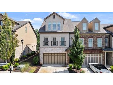 Beautiful townhome with brick and stucco exterior, two-car garage, and well-manicured landscaping at 117 Via Roma, Woodstock, GA 30188