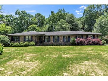 Charming brick home featuring lush lawn, mature trees, and meticulously maintained landscaping at 2532 Millbrook Dr, Snellville, GA 30078