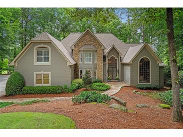 Stunning stone and stucco home with meticulously landscaped front yard in a serene wooded setting at 4435 Pemberton Cv, Johns Creek, GA 30022