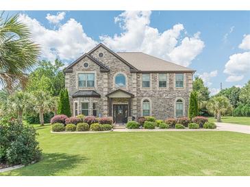 Beautiful two-story brick home featuring a manicured lawn, mature landscaping, and a welcoming entrance at 1405 Rainey Way, Hampton, GA 30228