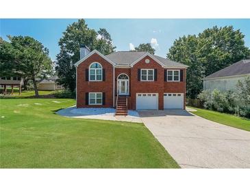 Inviting brick home featuring a two-car garage, manicured lawn, and a charming front entrance with decorative windows at 503 Rising Dr, Woodstock, GA 30189