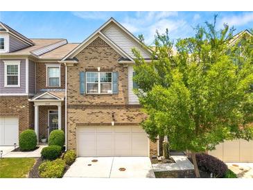 Two-story brick home with a front-facing garage, mature landscaping, and a well-manicured lawn at 3541 Ashcroft Se Dr, Smyrna, GA 30080