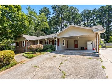 Charming single-story home featuring a large, cracked concrete driveway and carport at 824 Hickory Ridge Sw Rd, Lilburn, GA 30047