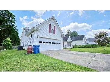 Charming two-story home featuring a white garage door and well-manicured lawn and colorful curb appeal at 2233 Hansford Pass, Buford, GA 30519