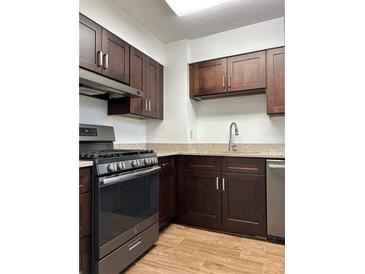 Well-lit kitchen with stainless steel appliances, granite countertops, and brown cabinetry at 2479 Peachtree Ne Rd # 317, Atlanta, GA 30305