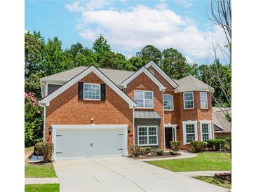 Traditional two-story red brick home with a manicured lawn, attached two car garage and a circular driveway at 2023 Jameson Cir, Lawrenceville, GA 30043
