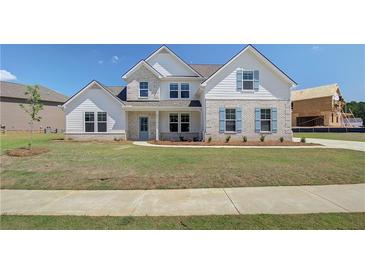Charming two-story home boasts white brick and siding, complemented by blue shutters and a well-manicured lawn at 443 Lothbury Ave, Locust Grove, GA 30248