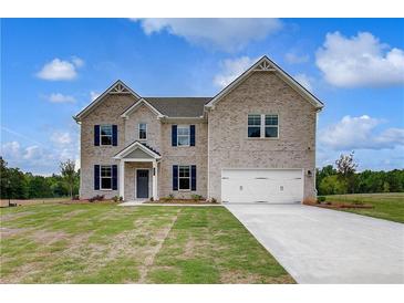 Beautiful two-story brick home with a two-car garage and manicured lawn on a sunny day at 145 Compass Rd, Hampton, GA 30228