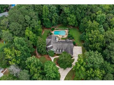 Overhead view of a beautiful house featuring a swimming pool nestled among lush greenery and mature trees at 140 Silvermere, Fayetteville, GA 30215