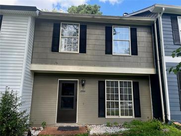 Two-story townhouse featuring a covered front porch, neutral color, black shutters and brick entry at 8564 Jamestown Way, Jonesboro, GA 30238