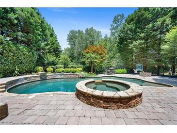 Stunning backyard pool with a connected jacuzzi, stone surround, and lush landscaping for outdoor entertainment at 307 Heritage Overlook, Woodstock, GA 30188