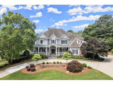 Beautiful two-story home featuring manicured front lawn and driveway with lush, mature landscaping and a welcoming front porch at 6325 Haddington Ln, Suwanee, GA 30024
