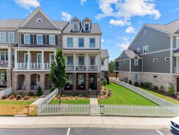 Charming townhome showcasing a manicured front yard, white picket fence and lovely brick and siding elevation at 630 Brashy St, Woodstock, GA 30188