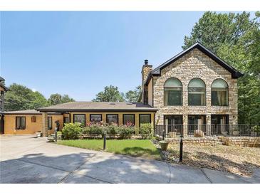 Beautiful stone home featuring an expansive front lawn with mature landscaping and a circular driveway at 1024 Lake Charles Dr, Roswell, GA 30075