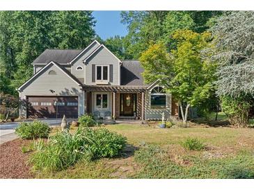 Charming two-story home with a well-manicured front yard and inviting pergola-covered entrance at 1270 Taylor Oaks Dr, Roswell, GA 30076