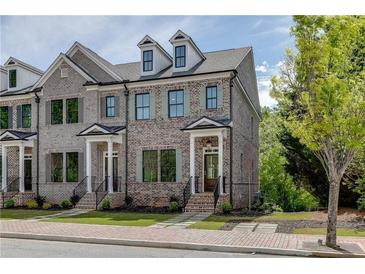 Charming brick townhome featuring a welcoming front porch and manicured landscaping at 130 W Main Street # 1, Buford, GA 30518