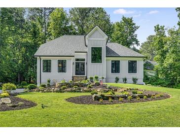 Charming home featuring professionally landscaped lawn with rock terracing, lush shrubs, and black frame windows at 6070 Lively Ct, Cumming, GA 30040
