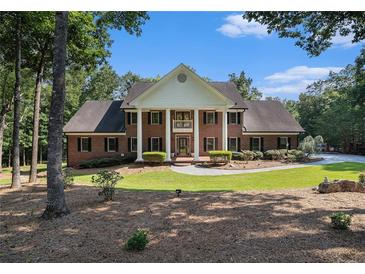 Classic red brick home featuring white columns, a manicured lawn, and mature trees at 402 Clyde Ct, Mcdonough, GA 30252