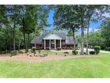 Charming brick home with a manicured lawn, mature trees, and a circular driveway at 402 Clyde Ct, Mcdonough, GA 30252