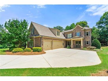 Stunning two-story brick home featuring a three-car garage, well-manicured lawn, and lush landscaping at 2317 Whiting Bay Courts Nw, Kennesaw, GA 30152