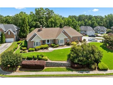 Well-maintained brick home with a manicured lawn and mature trees providing shade and curb appeal at 2012 Arbor Springs Way, Buford, GA 30519