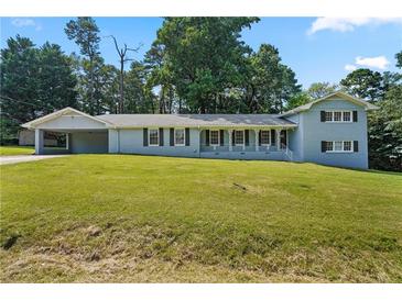 Charming, light blue house with a covered carport and a well-maintained lawn and front porch at 1260 White Oak Se St, Conyers, GA 30013