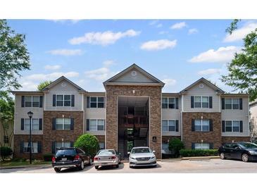 Exterior shot of the apartment building, showing the parking lot and some parked cars at 3303 Par Three Way, Lithonia, GA 30038